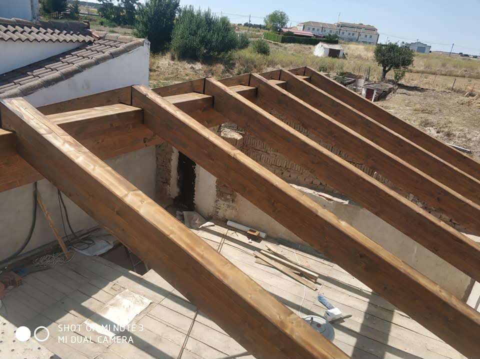 Muro de ladrillo y estructura de madera de cubierta en construcción